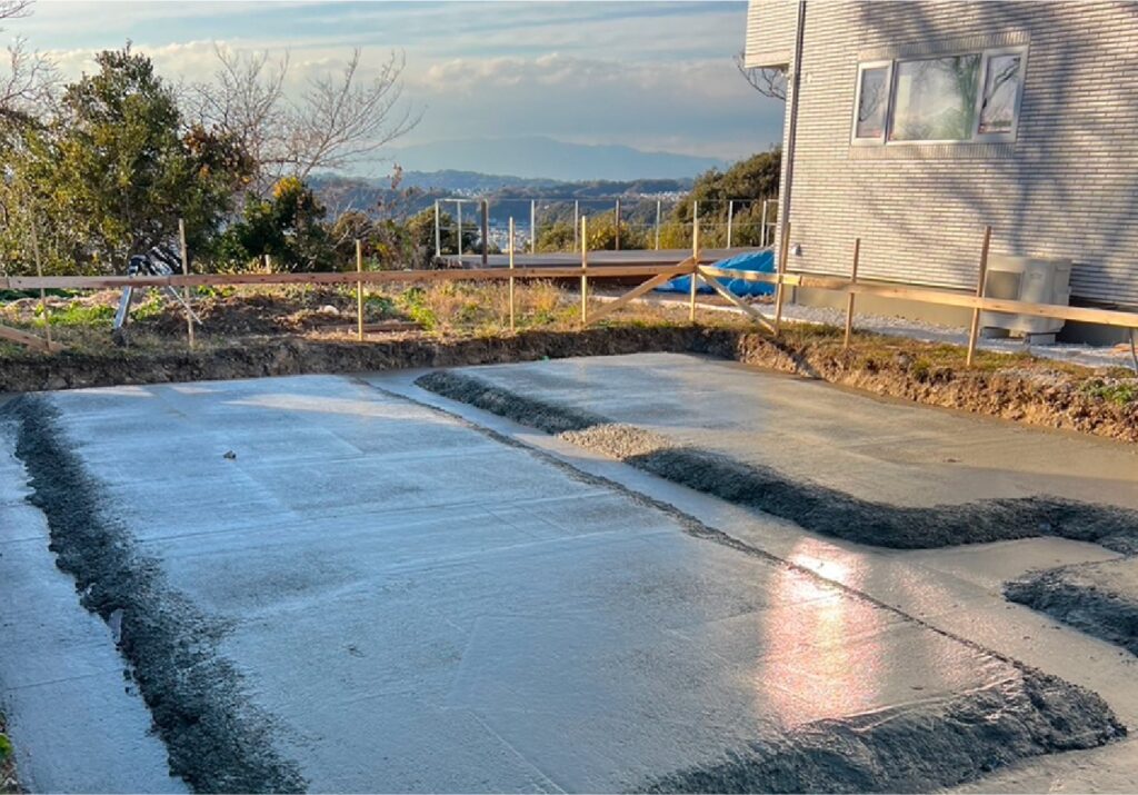 基礎にコンクリートを流したばかり向こう側に山が広がっている